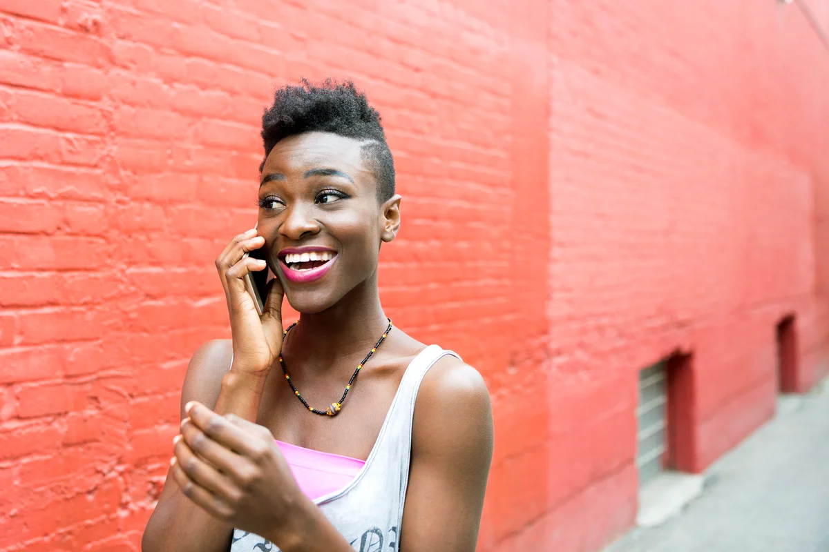 Cool young woman talking on cell phone at urban brick wall