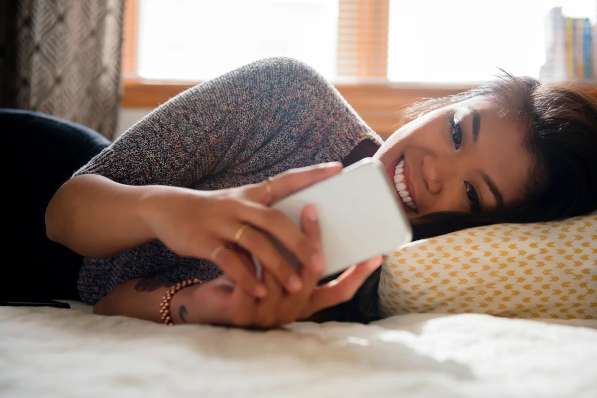Woman laying on bed with cell phone