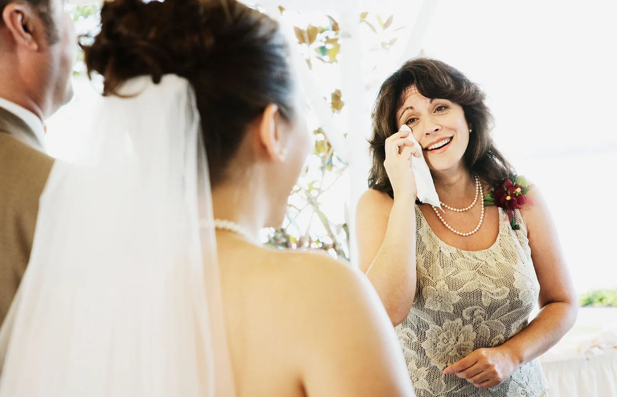 Crying woman watching bride walk down aisle