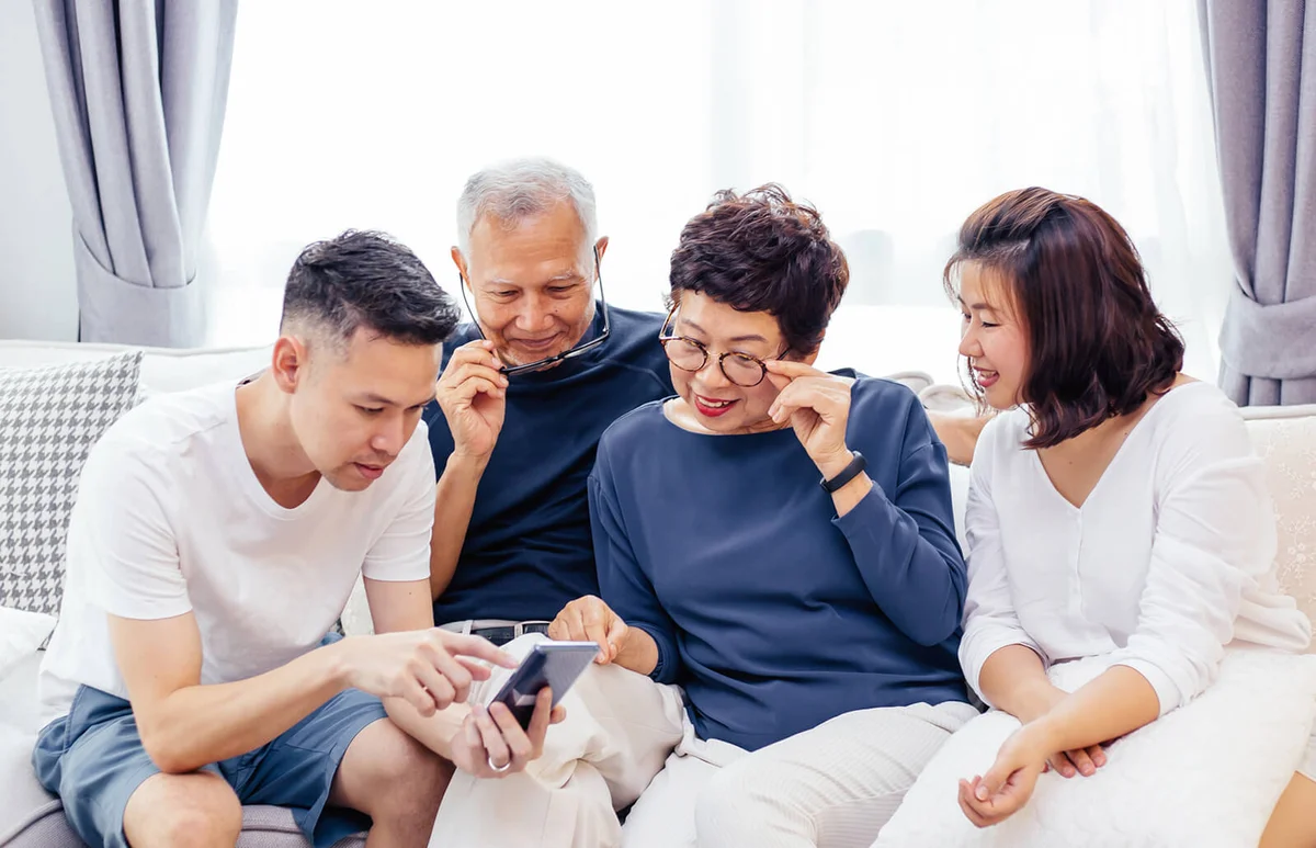 family with adult children and senior parents using a mobile phone