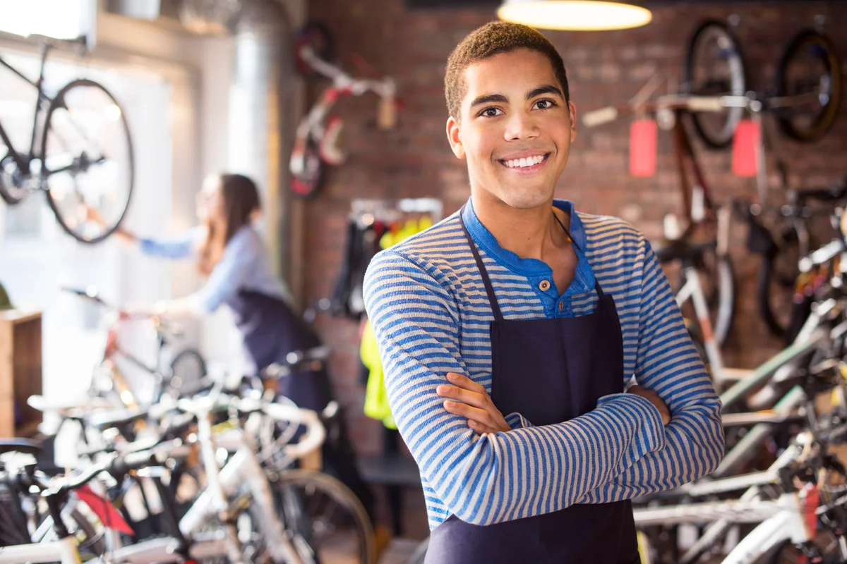 Bike shop teen worker stands proudly in front of his stock