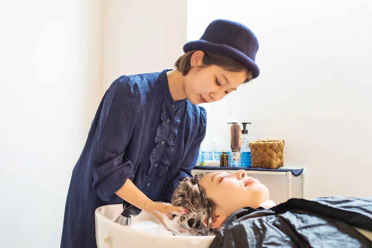 Teen hairdresser shampooing a woman