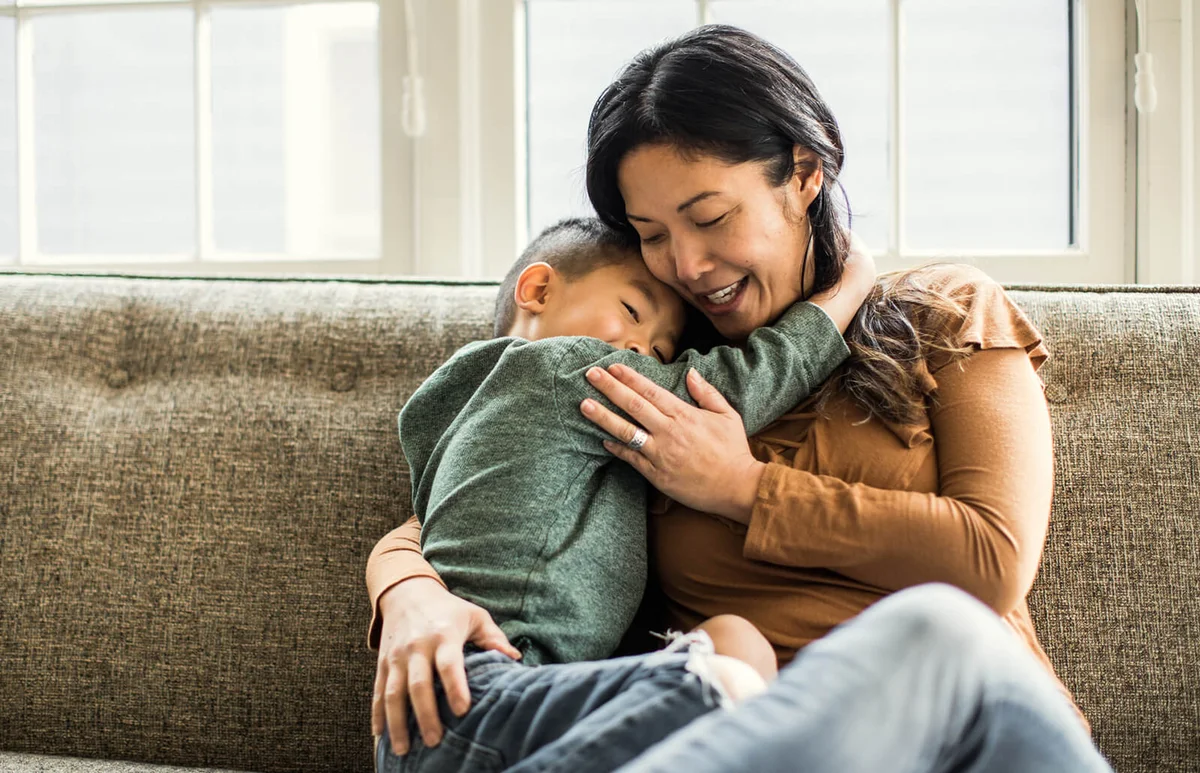 Mother hugging son on couch