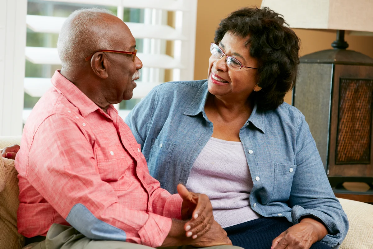 Happy Senior Couple Sitting On Sofa At Home