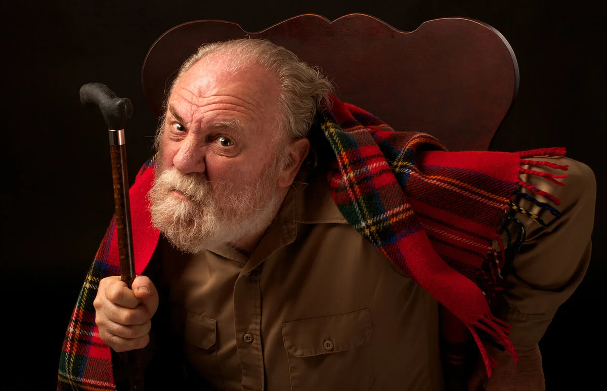 Grumpy old man shakes his cane and frowns