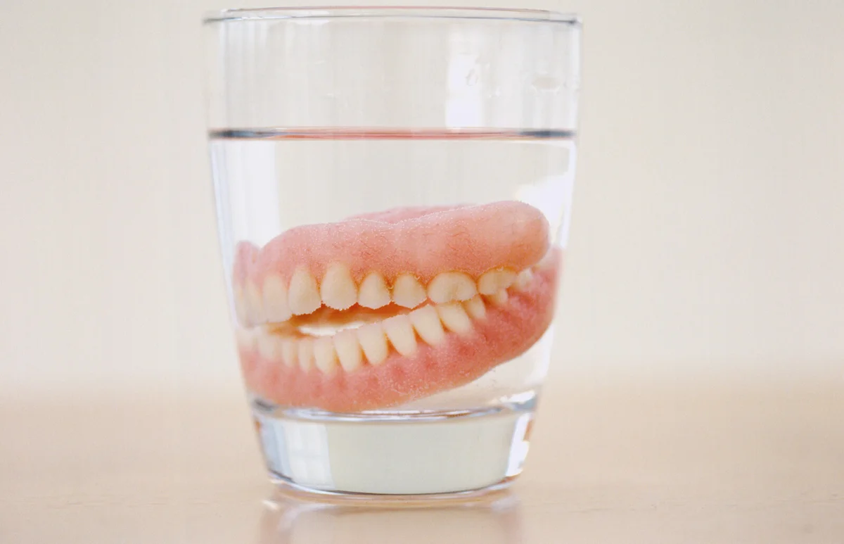 set of dentures in a glass of water