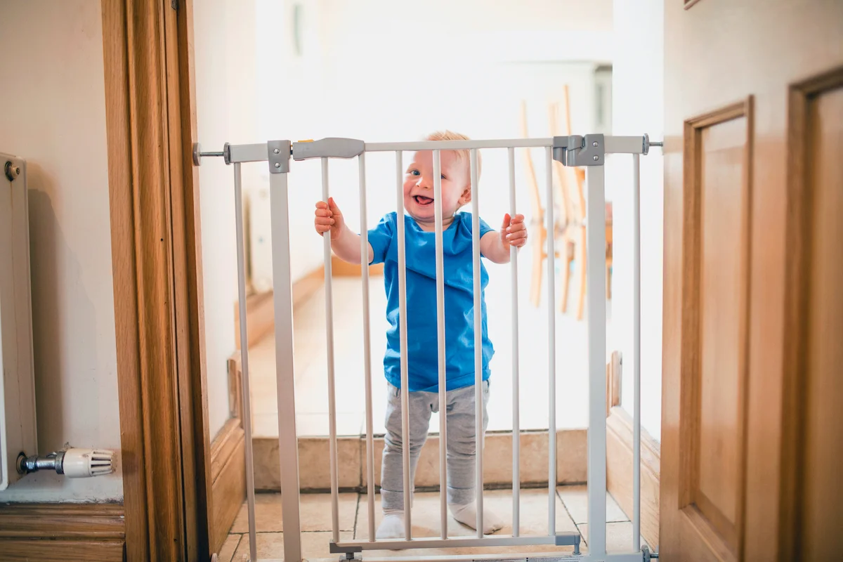 Small Boy Holds On To Safety Gate