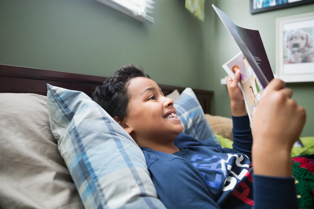 Boy reading magazine in bed