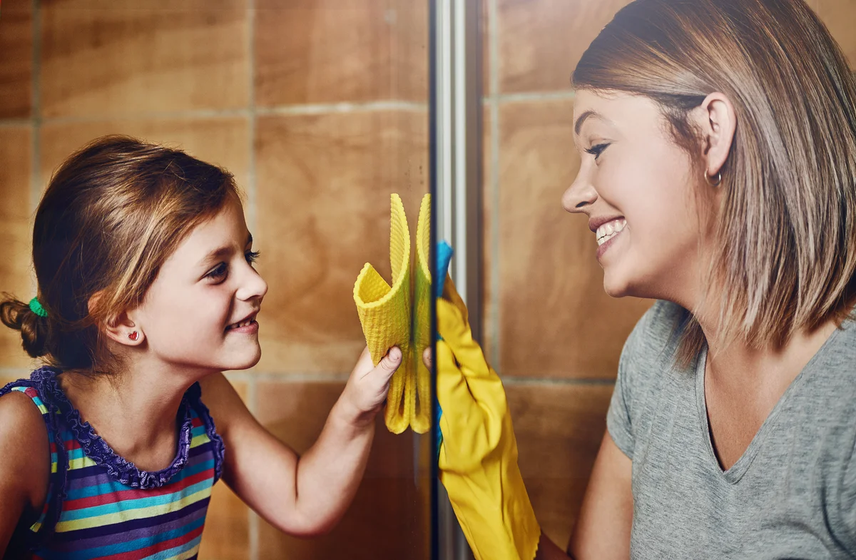 Mom and daughter cleaning glass shower