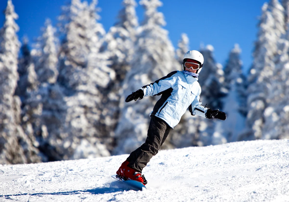 Teenage girl snowboarding on sunny winter day