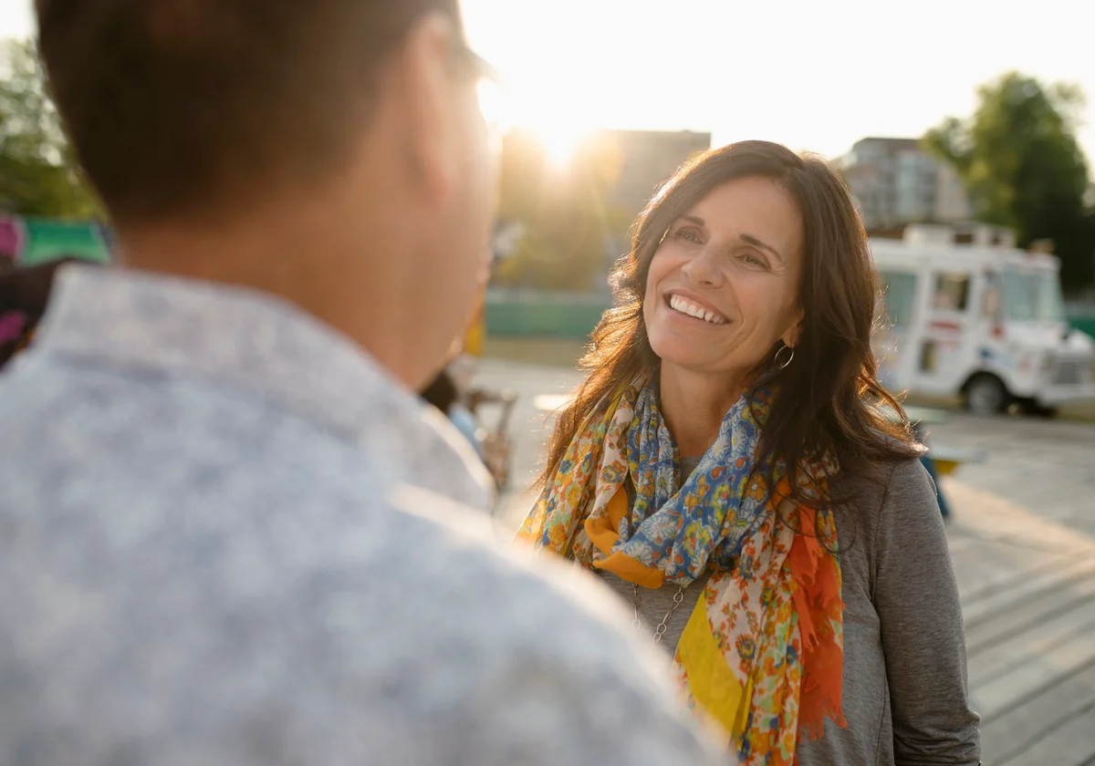 Smiling woman talking with man in sunny park