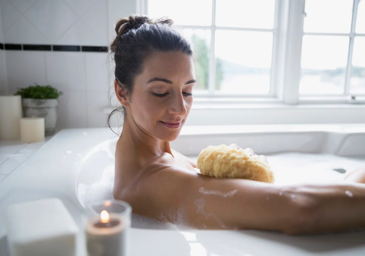 Woman using sponge in bubble bath