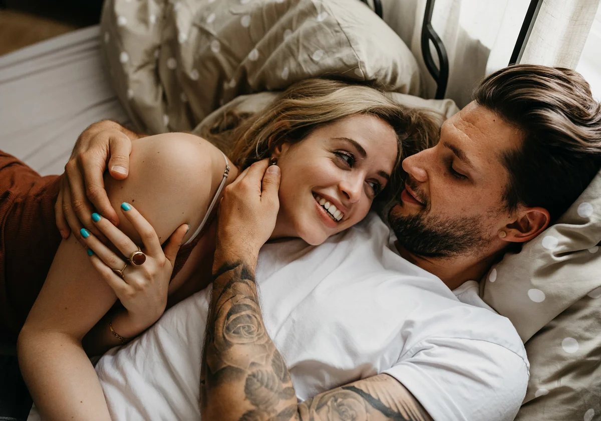 Loving Young Couple Lying On Bed At Home