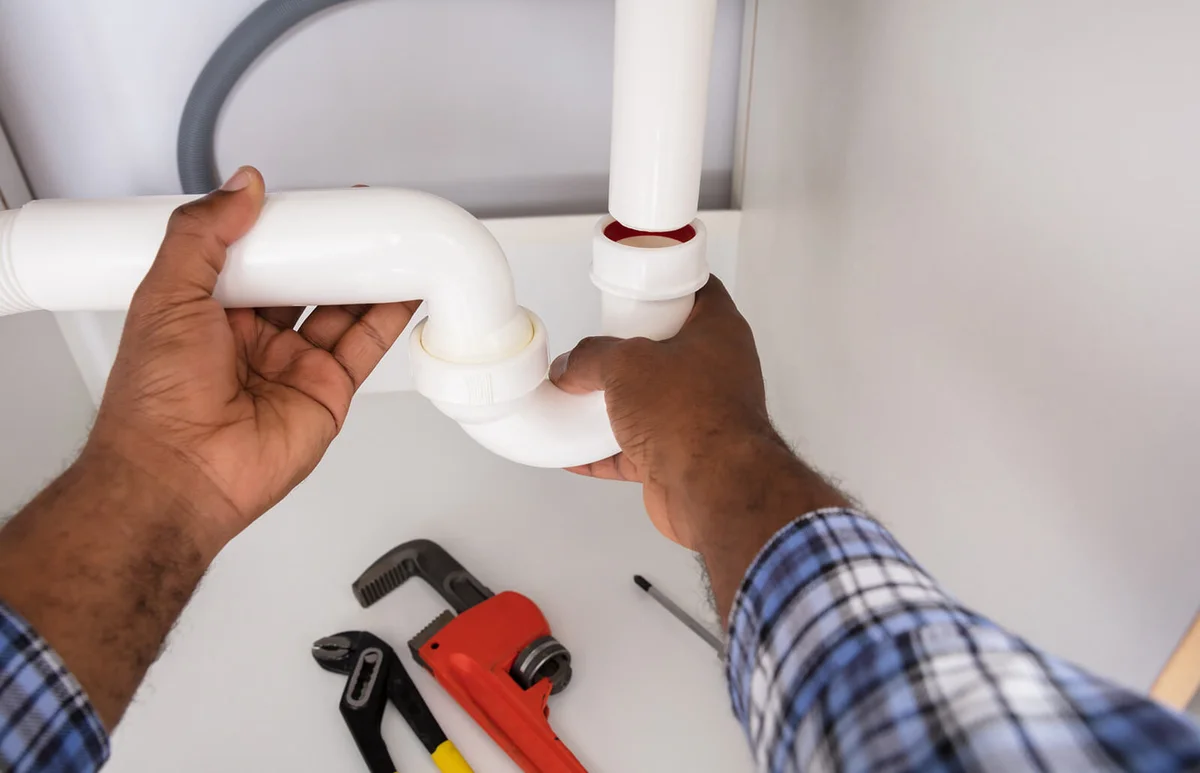 Plumber Fitting Sink Pipe In Kitchen