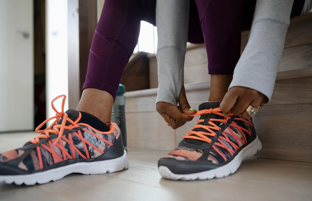 Senior woman tying shoelaces, preparing for a run