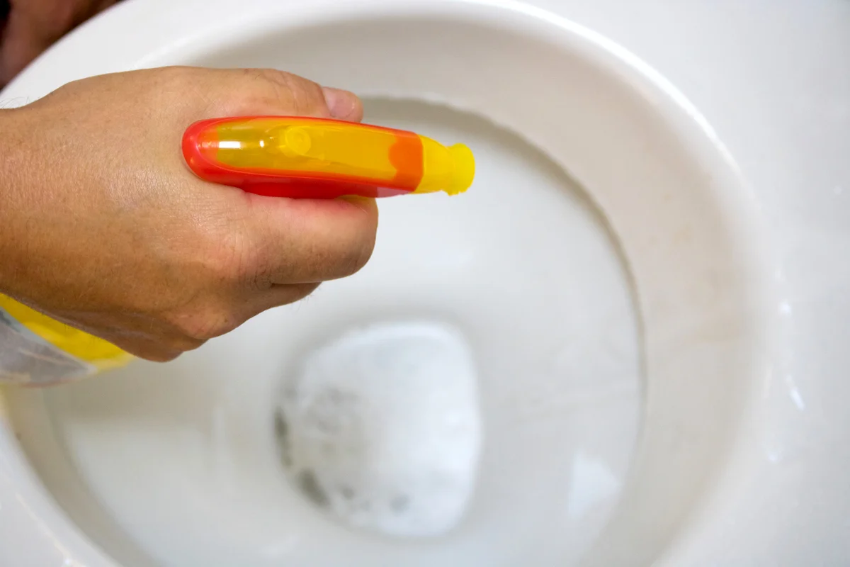 Cropped Hand Cleaning Toilet Bowl With Spray Bottle