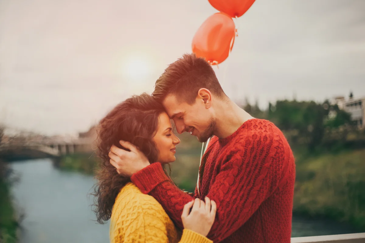 Young couple celebrating love and holding heart shaped balloons