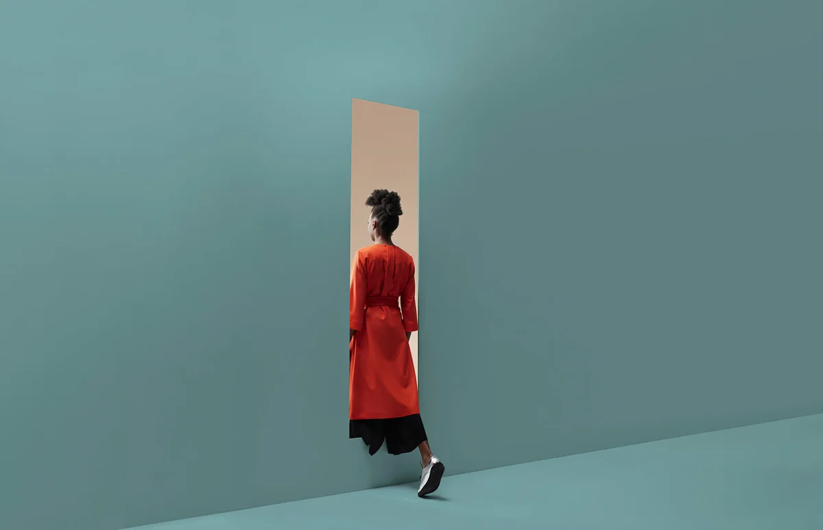 Woman walking into rectangular opening in coloured wall
