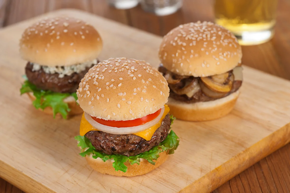 Three sliders on cutting board with beer