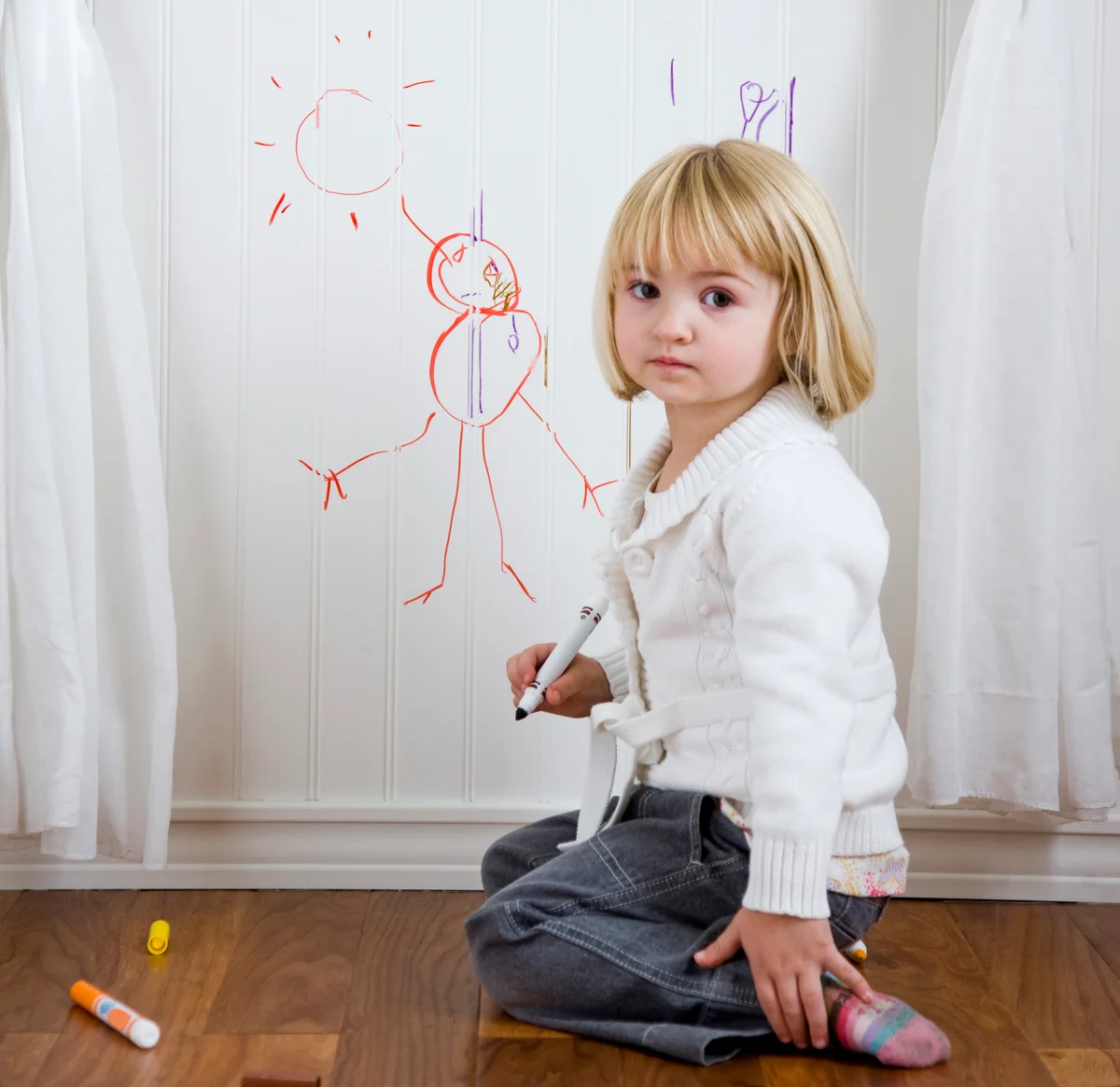 child drawing on the wall with markers