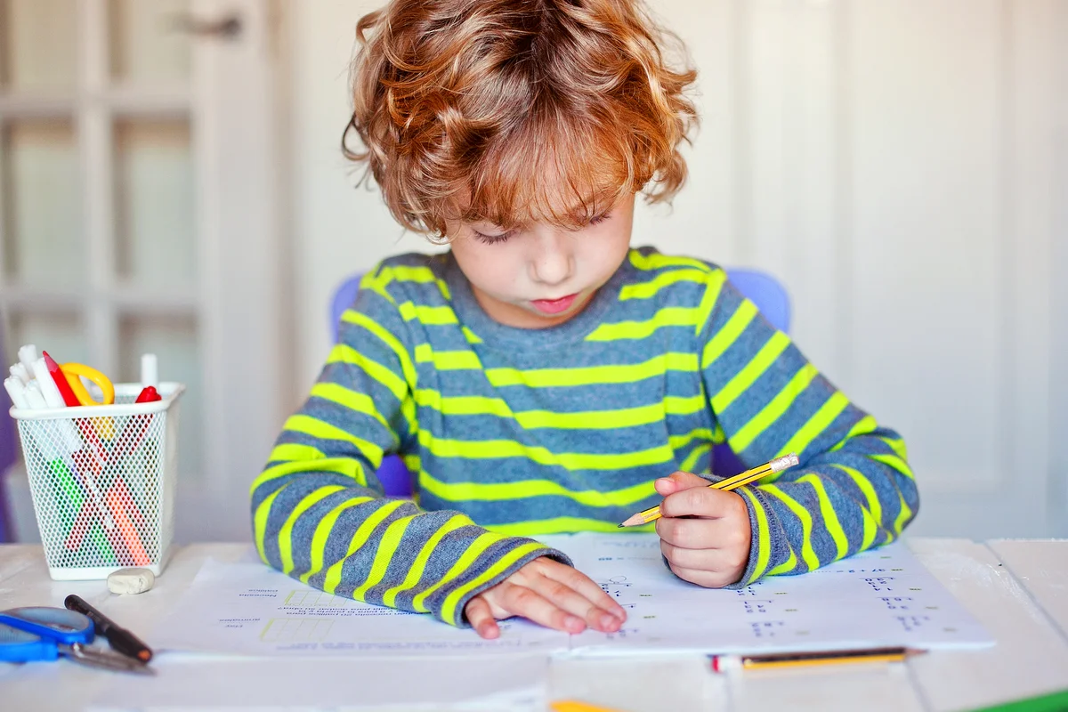 Blonde boy concentrated in his math homework at home