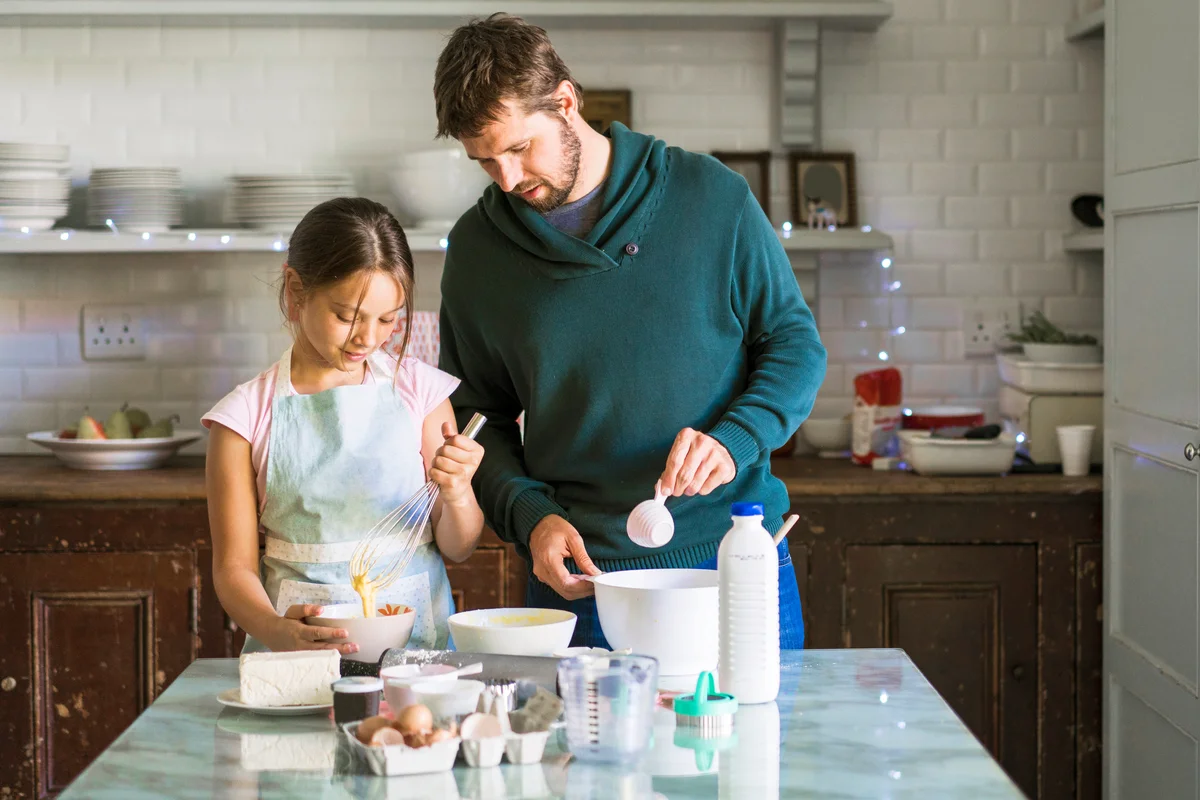 Father is assisting daughter baking in kitchen