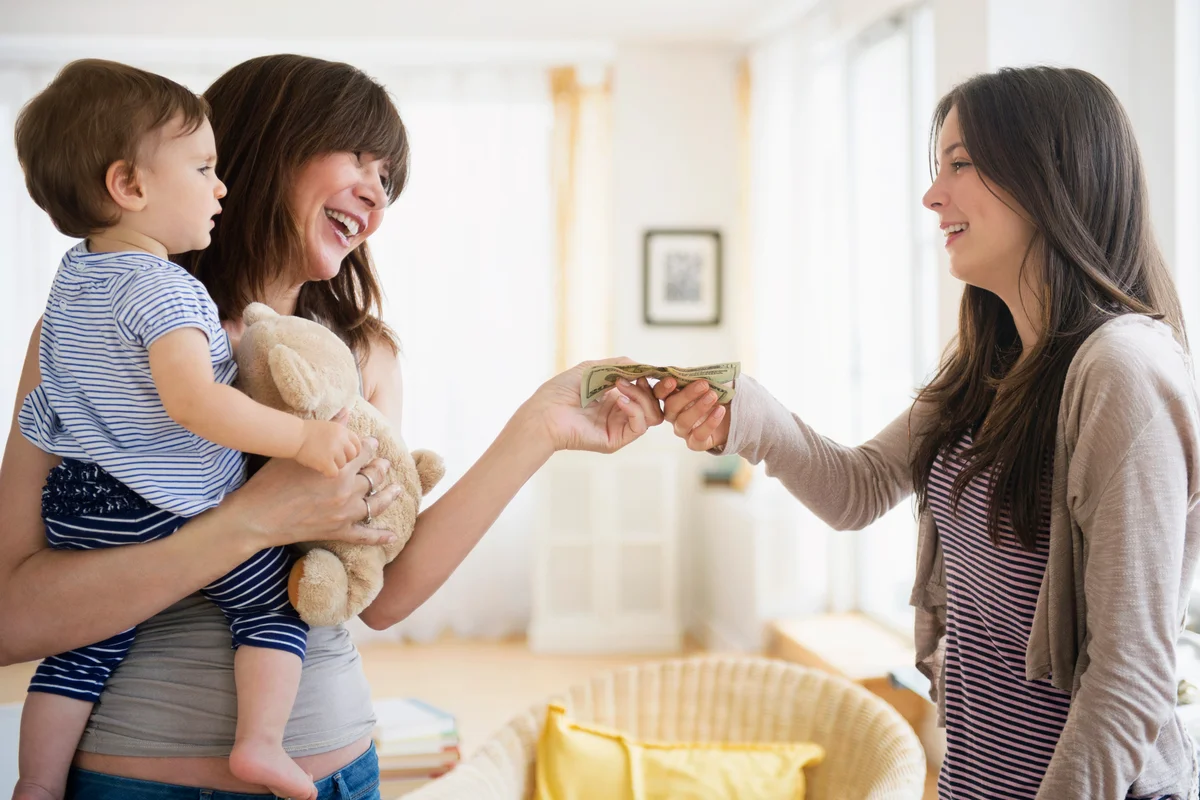 Woman paying teenage nanny for taking care of her son