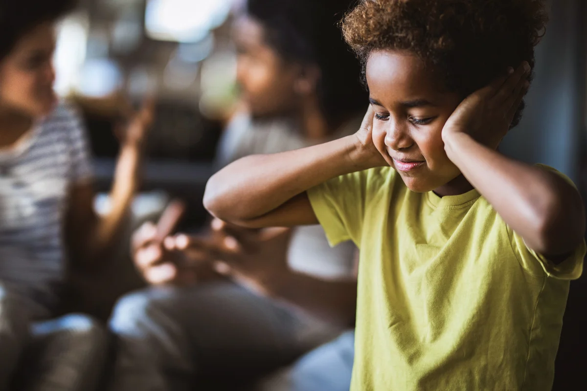 Girl covering her ears while refusing to listen her parents arguing