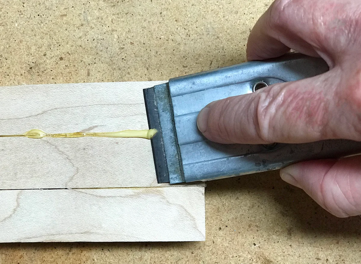 Scrape glue off wood with blade