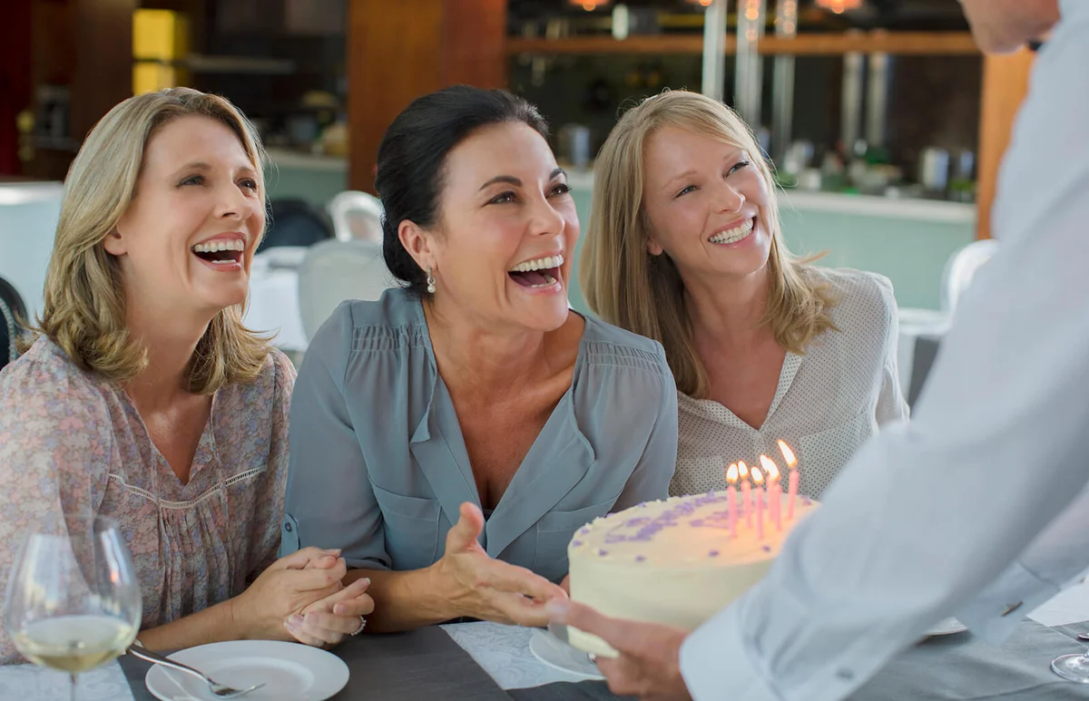 Man handing birthday cake to women