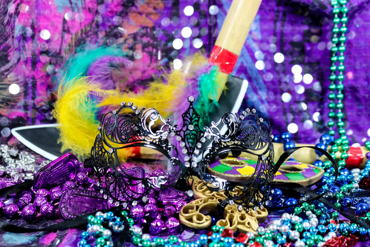 Mardi Gras Carnaval background with black filigree mask, beads, and feathered bamboo spears