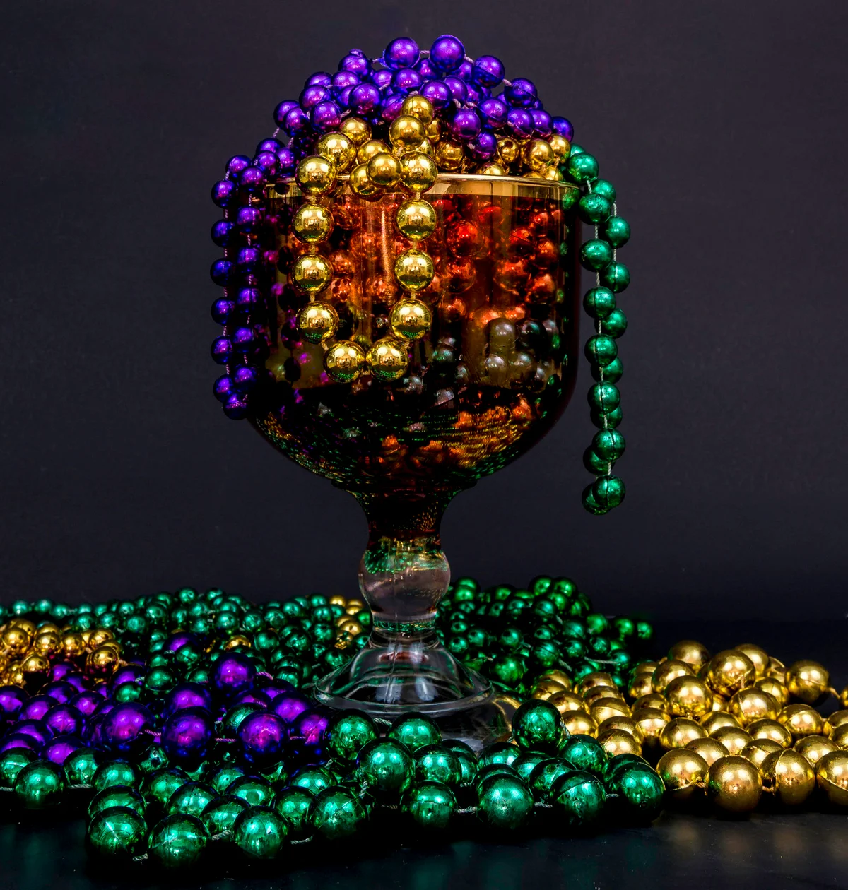 Mardi Gras beads overflowing a glass goblet