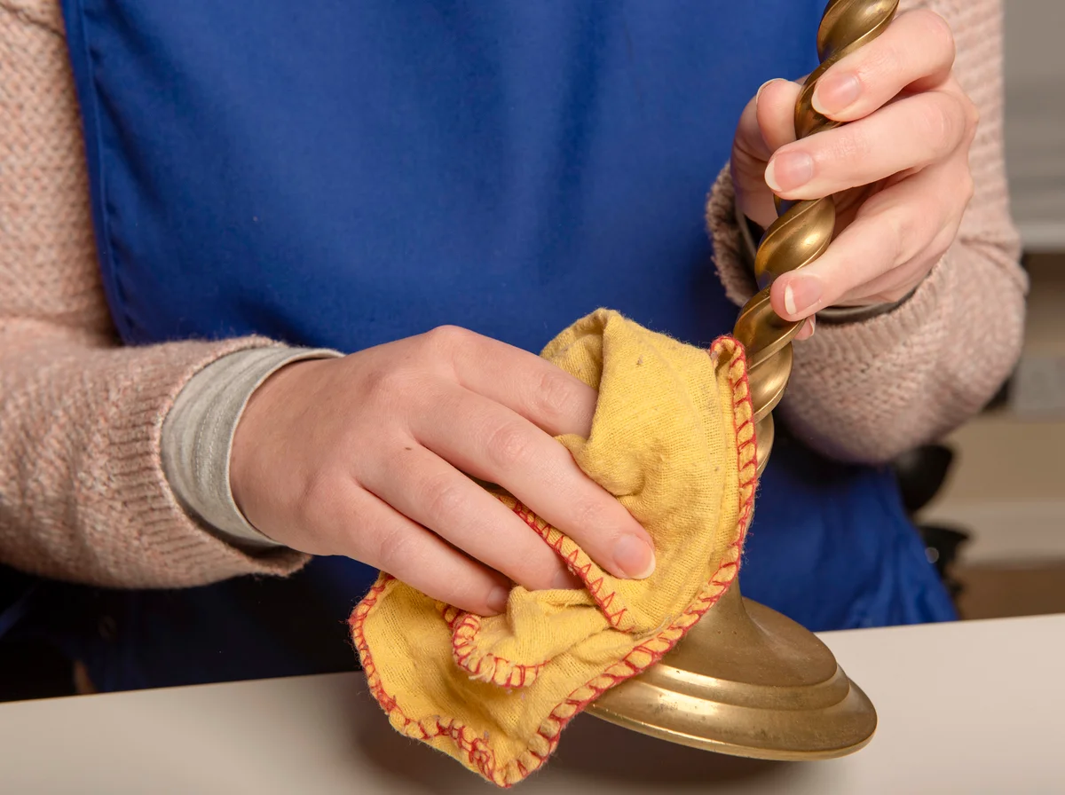woman cleaning brass candle sticks