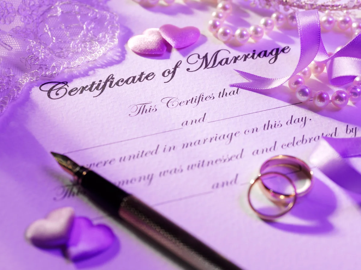 Certificate of marriage with rings, pen, hearts and a pearl necklace