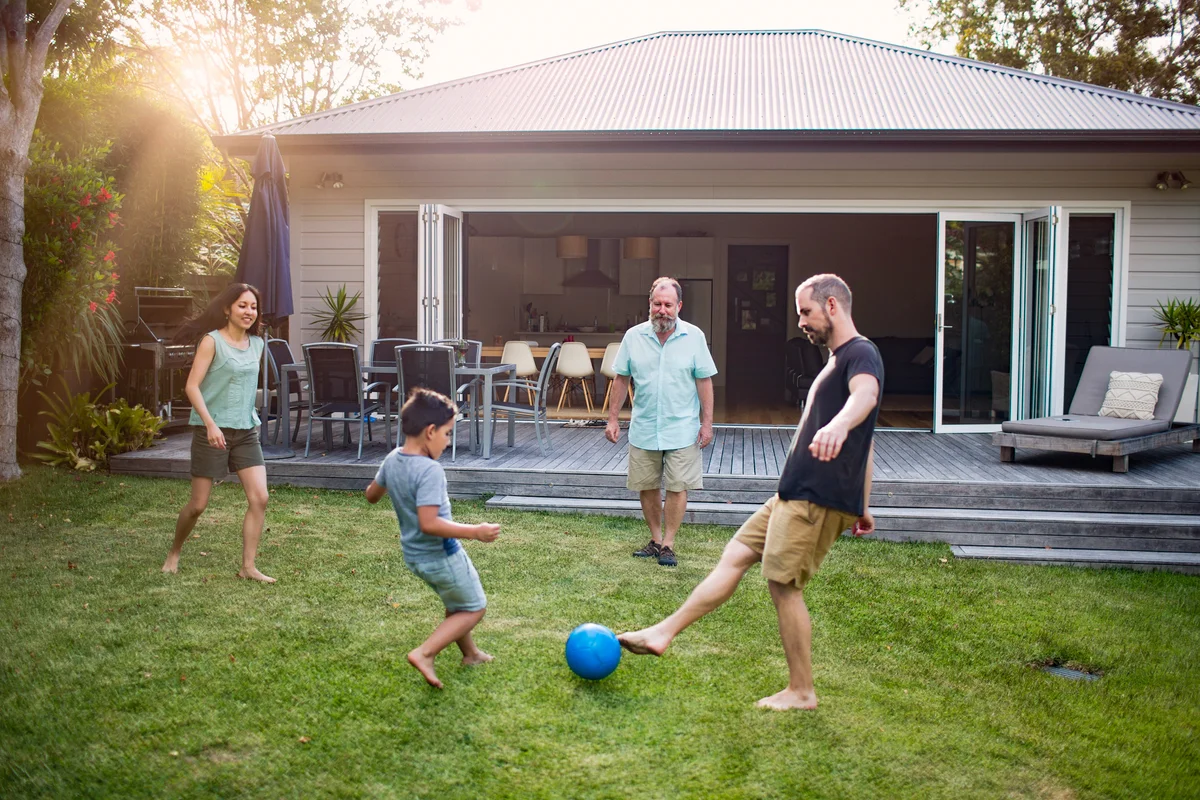 Multi-generation family playing soccer in yard