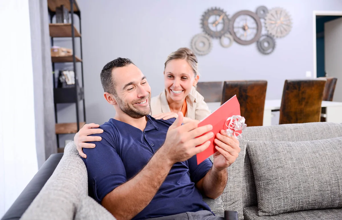 Woman giving surprise present invitation in envelope gift to her boyfriend