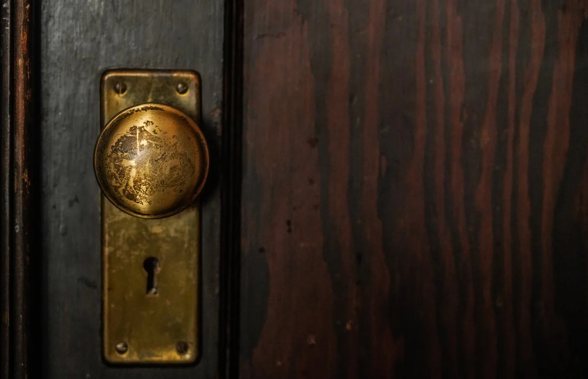 Weathered and old brass door knob on wooden door