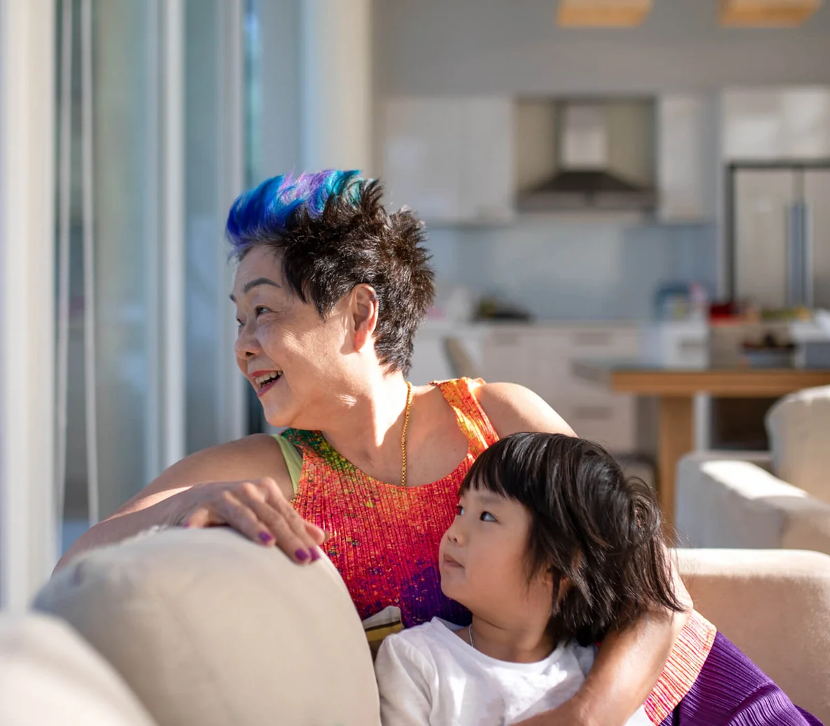 Granddaughter And Grandmother Resting On Sofa At Home
