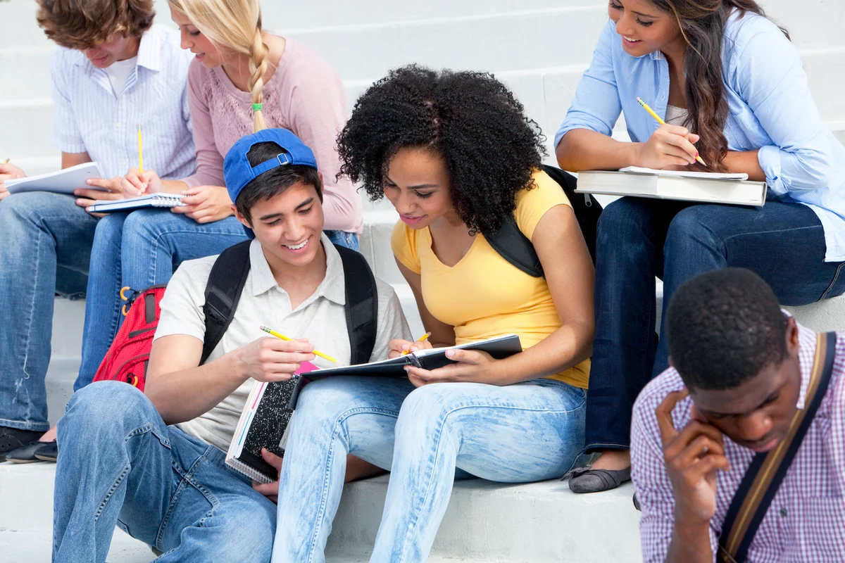 Group of students studying on steps of school building