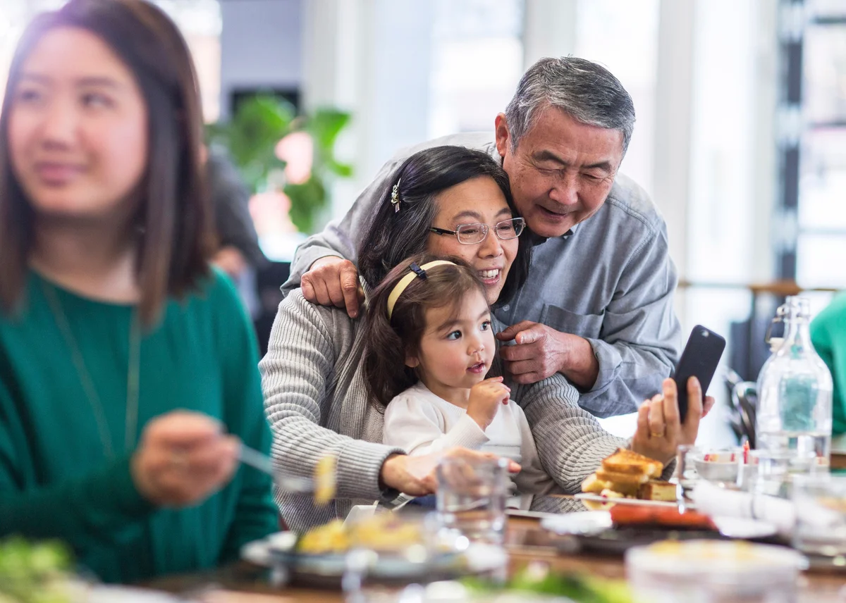 Grandparents taking selfie with granddaughter in restaurant
