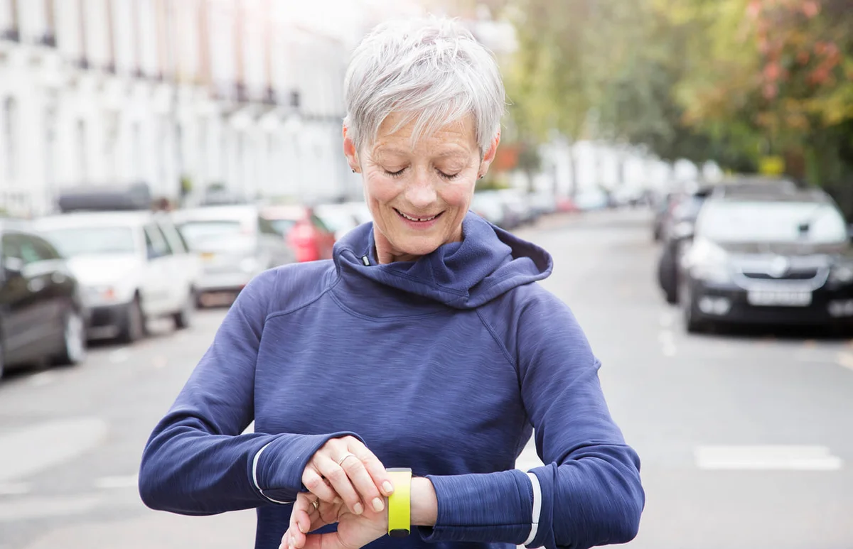 Female senior runner checks activity tracker