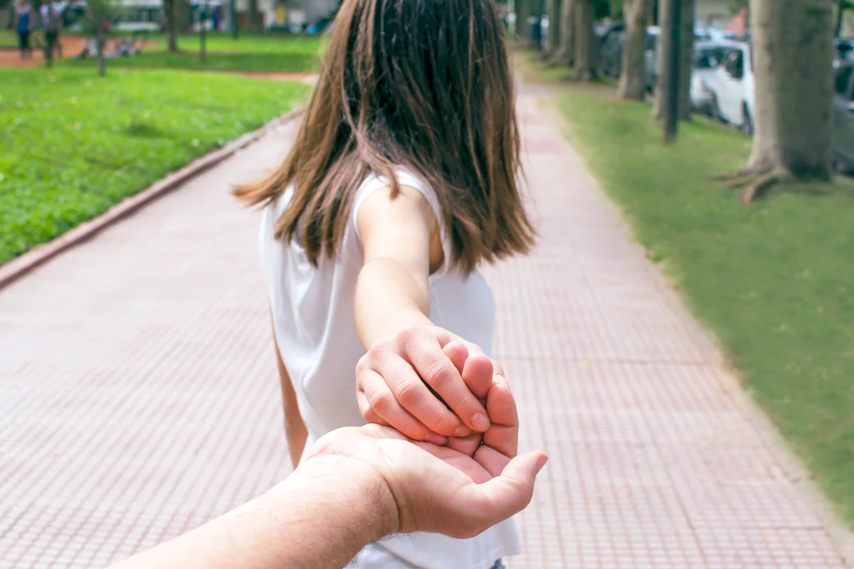 Rear view of a girl holding her father's hand