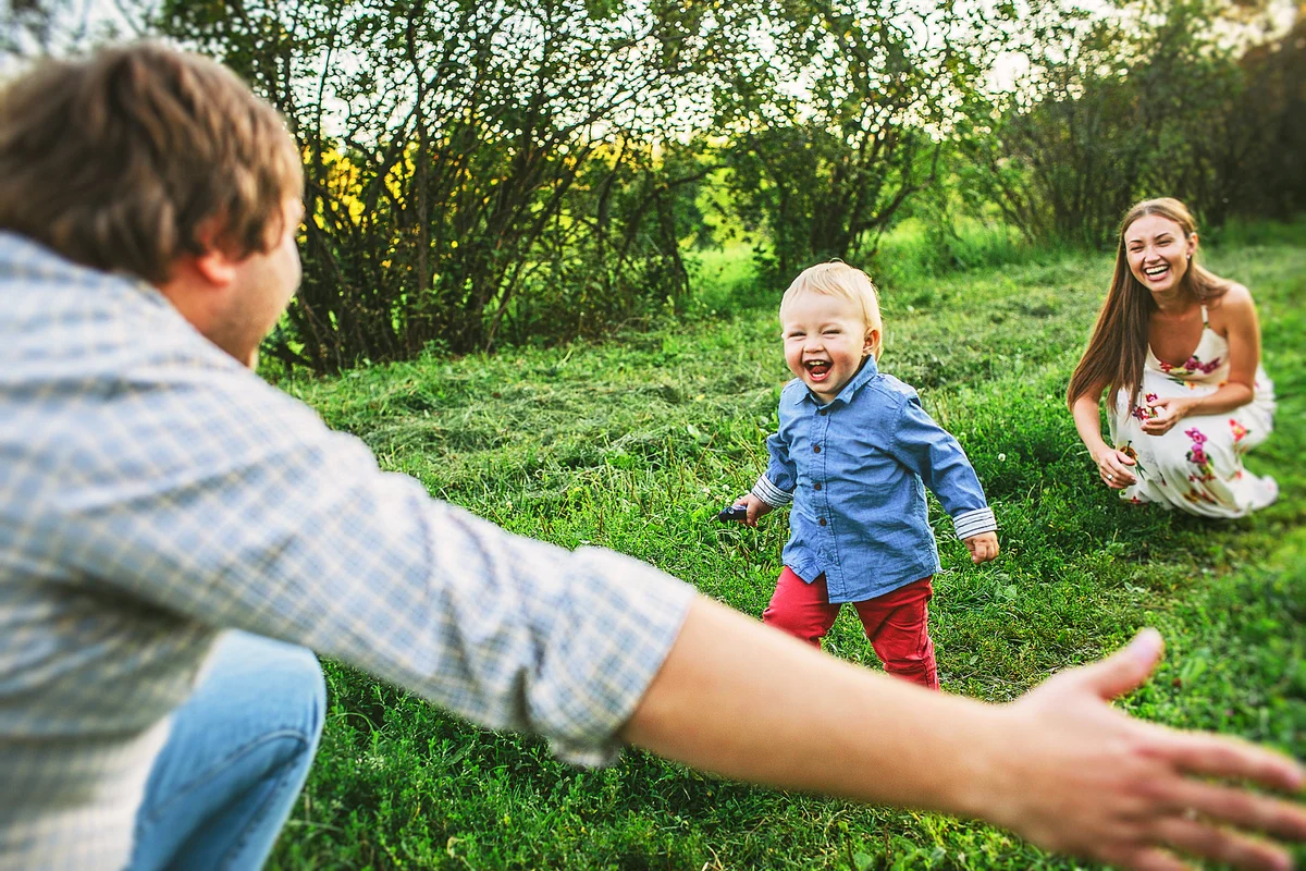 Two parents with little toddler son 1 year old playing outdoors