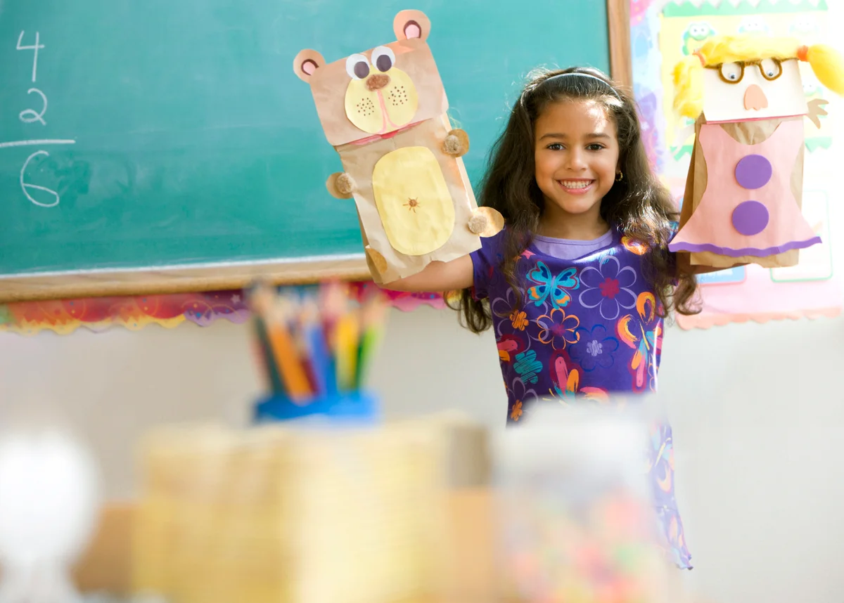 Girl holding sack puppets in classroom