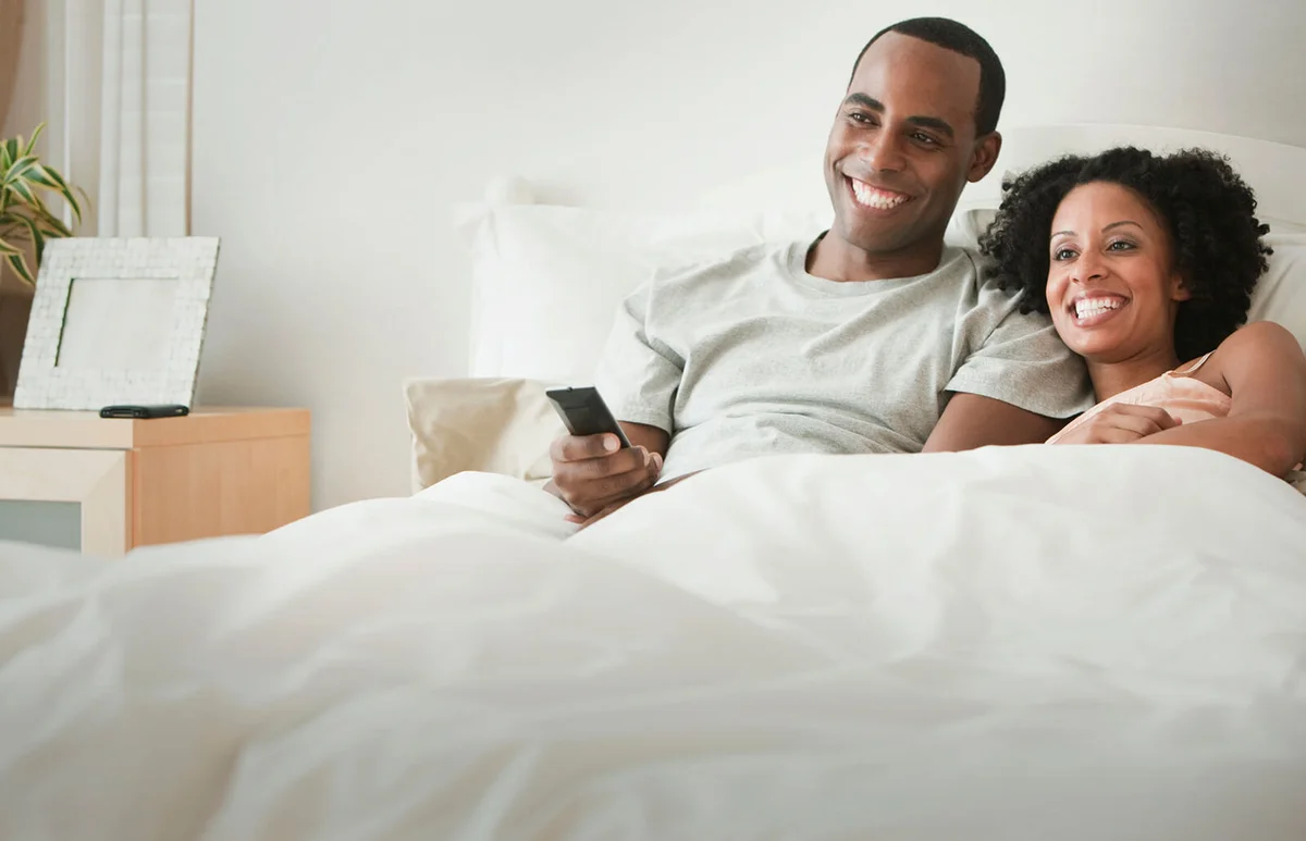 Couple laying in bed watching television