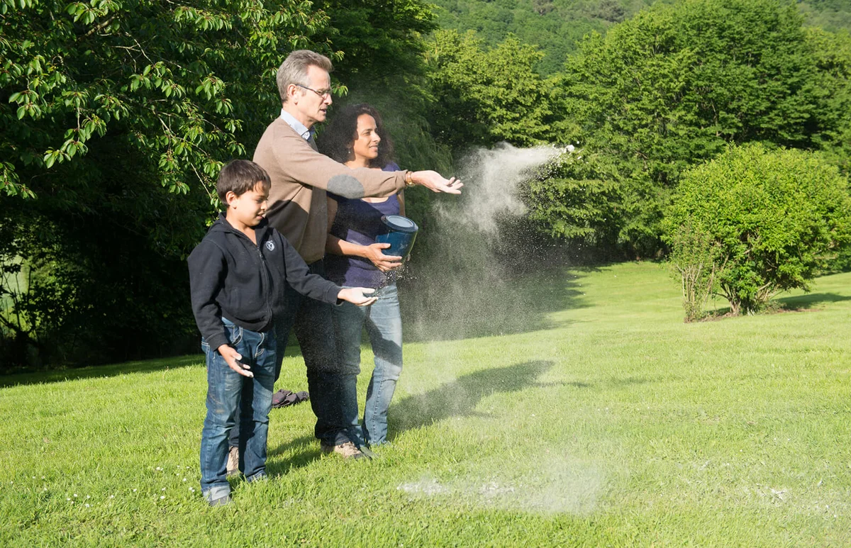 Family scattering ashes in a garden