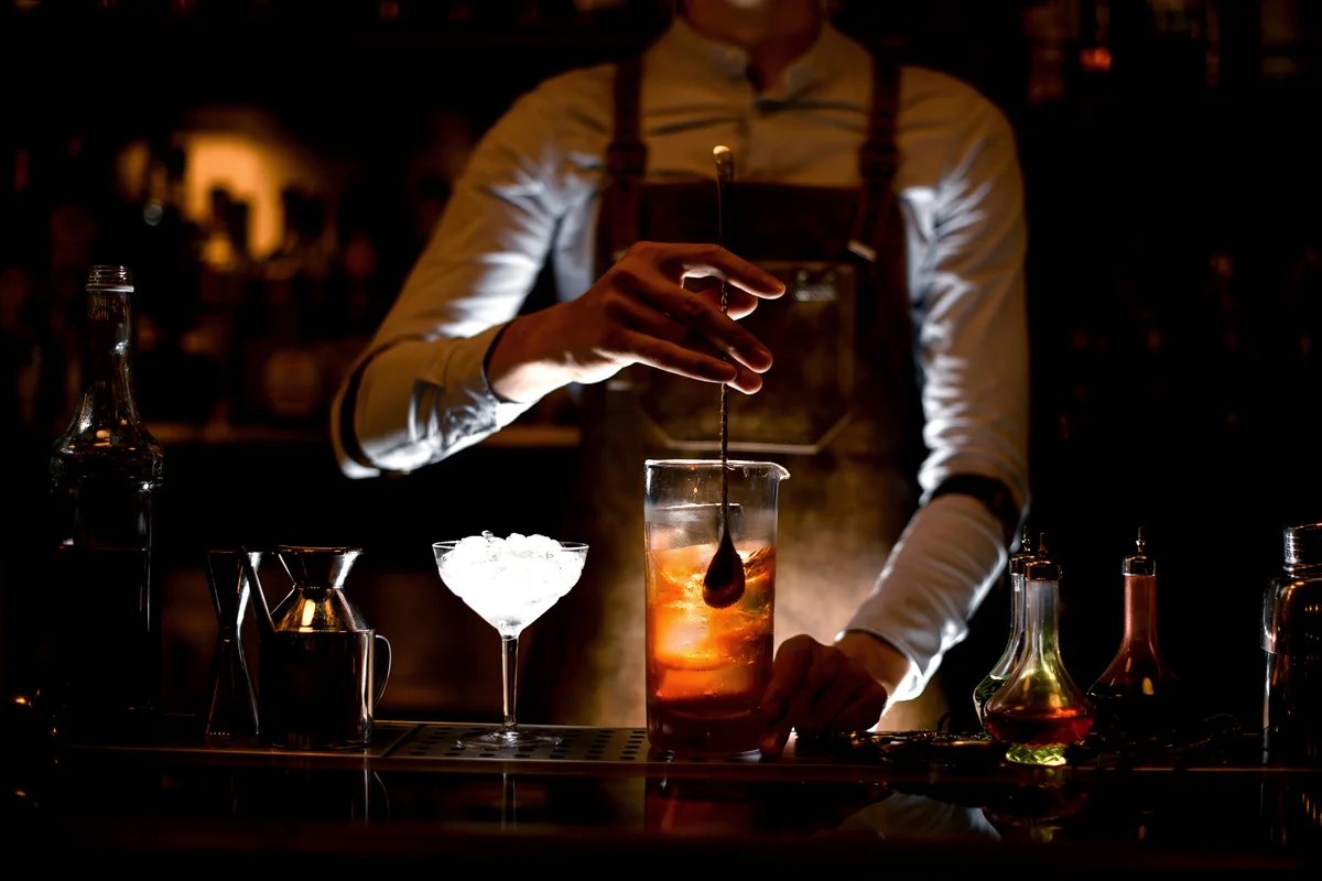 Bartender stirring alcohol cocktail with a spoon