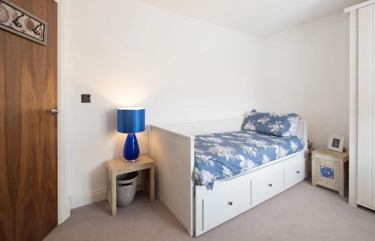 single bedroom with white walls and blue floral bedding inside of a home