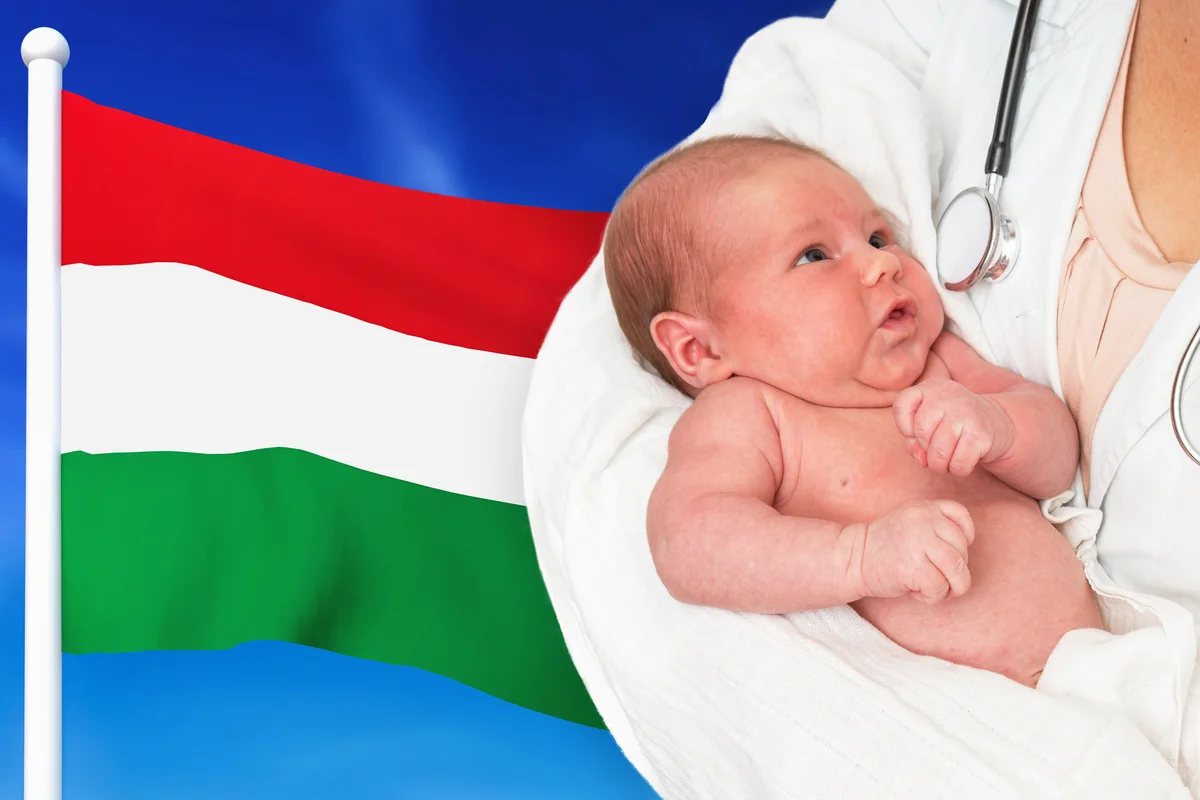 Newborn baby in hands of doctor with Hungary national flag