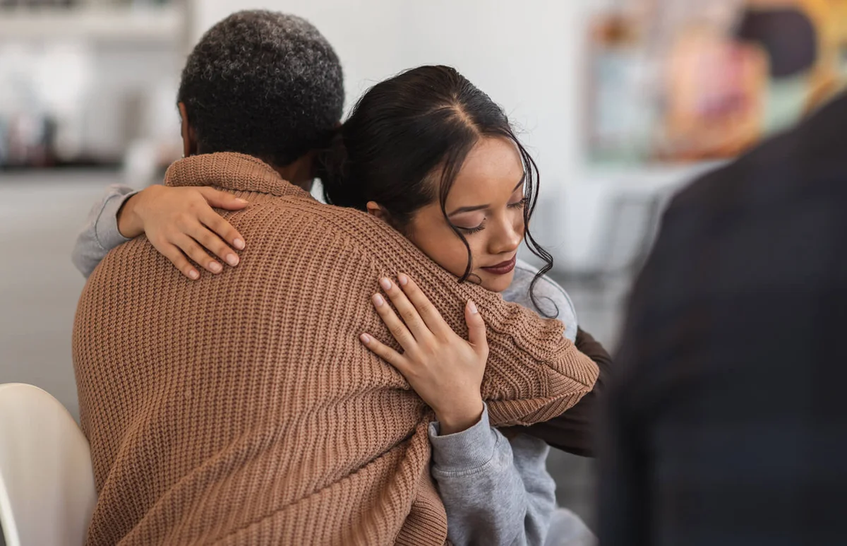 Supportive women hug while attending a group therapy session